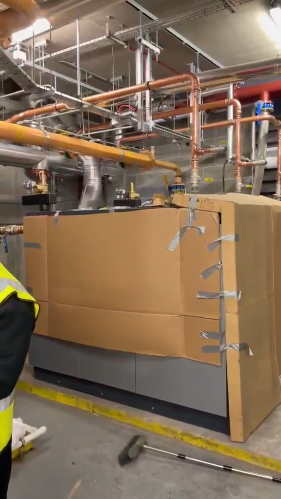 Commercial boilers still in their protective wrapping, with new copper and gas pipework above them, in a London plant room on a Neos Engineering job